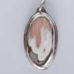 Pendant with oval gem, peach color drips onto white, gray along bottom, set in sterling silver