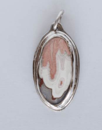 Pendant with oval gem, peach color drips onto white, gray along bottom, set in sterling silver